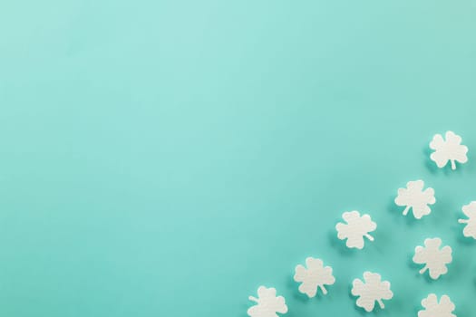 Happy St. Patrick's Day decoration background. Flat lay of cutting paper clover leaves festive decor, shamrocks leaves holiday symbol with copy space on colour background, Banner greeting card concept