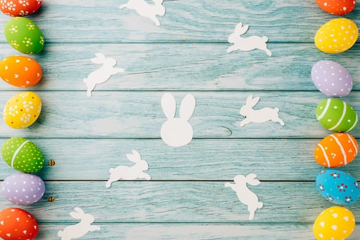 Easter Day Concept. Top view holiday banner background web design white colorful easter eggs and paper bunny rabbit on blue wood background with copy space, celebration greeting, overhead, template
