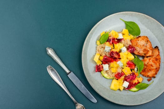 Appetizing salad with chicken meat, orange, mango and quinoa
