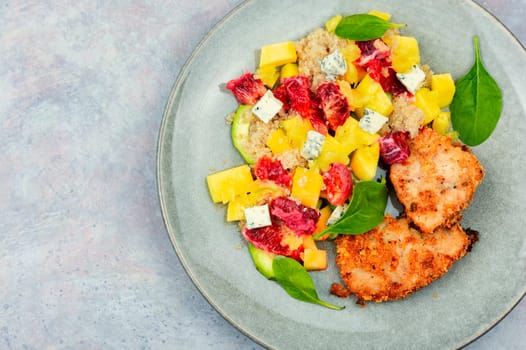 Appetizing salad with chicken meat, orange, mango and quinoa