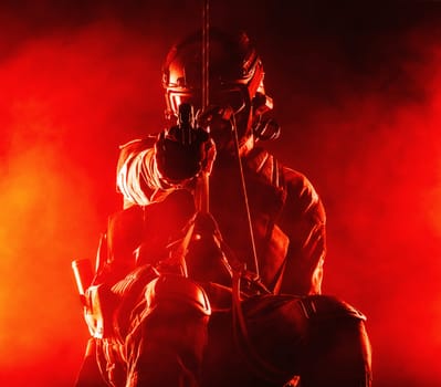 Silhouette of police officer in tactical gear descending from a height, rope exercises with weapons. Tactical rappelling, anti-terror or counter terrorism operation in darkness in rappelling harness