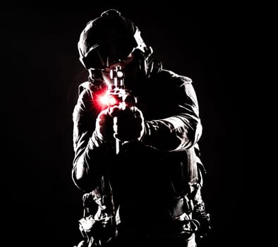 A contour silhouette of a soldier fighting in the darkness. Respect for the sacrifices made by soldiers in defense of their country motherland, symbol of strength and courage. Gun with laser sights, red light