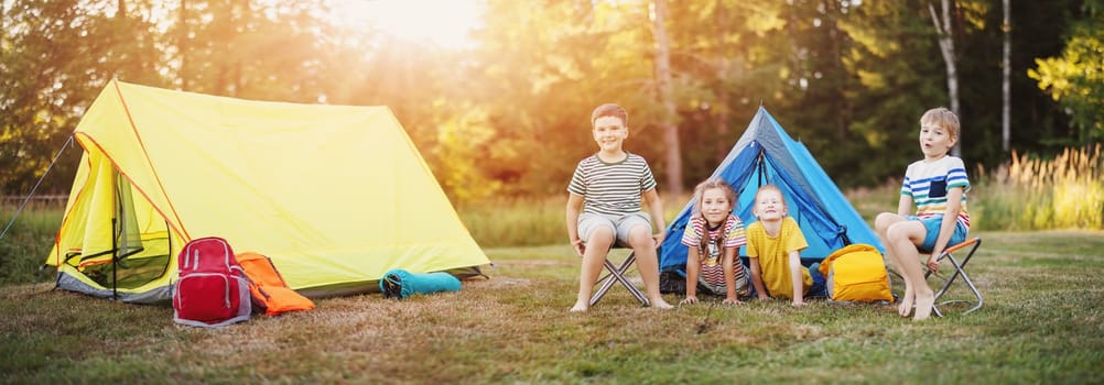 Group of children resting in the campground in nature. Concept of the family vacation, recreation and scouts camping.