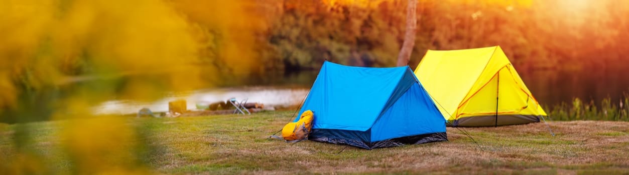 Panoramic view of the campground with colourful tents near the lake in wilderness park. Concept of the camping and active vacation.