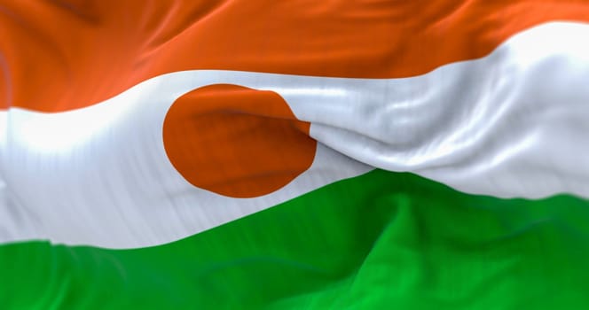 Detail of the Niger national flag waving. Orange, white, and green stripes with orange disc in the center. 3d illustration render. Selective focus. Close-up. Textured fabric background