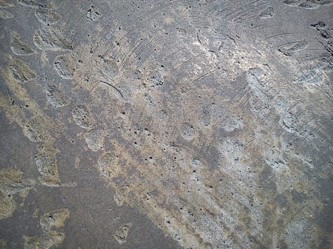 Roughly machined metal surface with craters and scratches. Dark gray metal with gold streaks and gray ovals.