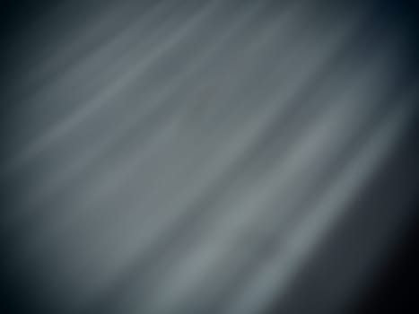 Diagonal rays of light on a gray background. Blurred abstract background light effect, light leaks. Side surface illumination. Small sparks and glow. Shine, glint or glare.