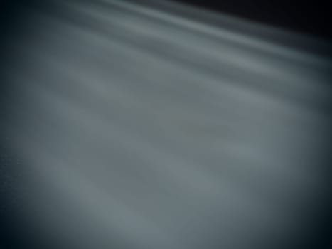 Diagonal rays of light on a gray background. Blurred abstract background light effect, light leaks. Side surface illumination. Small sparks and glow. Shine, glint or glare.