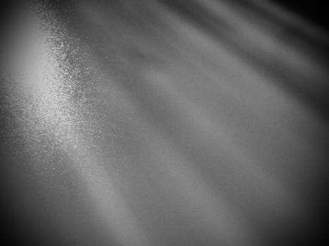 Abstract gray background. Oblique light rays on a gray background with flickering dots. From left to top, the lines are directed down and to the right. Coarse grain. Glow, flare or shine