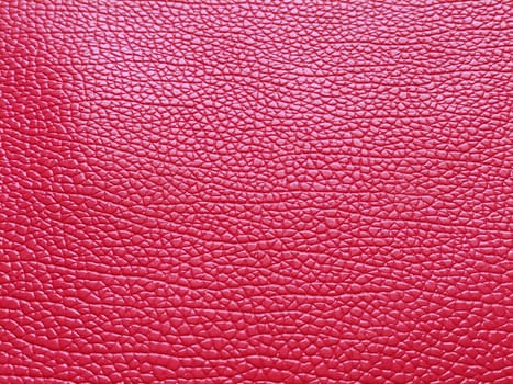 Faux red leather. Separate grooves and elevations on the surface of a bag or shoe. Reflection of the light. Fashion accessory made of faux pig skin. Close-up