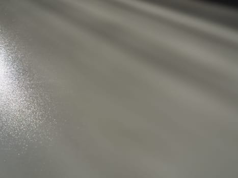 Diagonal rays of light on a gray background. Blurred abstract background light effect, light leaks. Side surface illumination. Small sparks and glow. Shine, glint or glare. Left top right down