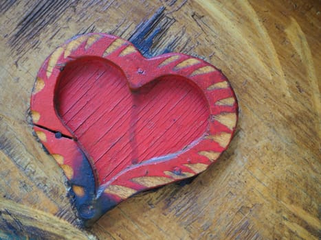 Carpentry heart shape on a wooden surface and painted red. A symbol of love and fidelity. Postcard for congratulations or recognition on Valentines Day. Signs of the influence of ignition or moisture