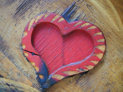 Carpentry heart shape on a wooden surface and painted red. A symbol of love and fidelity. Postcard for congratulations or recognition on Valentines Day. Signs of the influence of ignition or moisture
