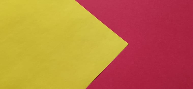 A yellow sheet of paper is laid sideways on a red sheet of paper. Thick paper or thin cardboard. The yellow element is on the left and the red is on the right