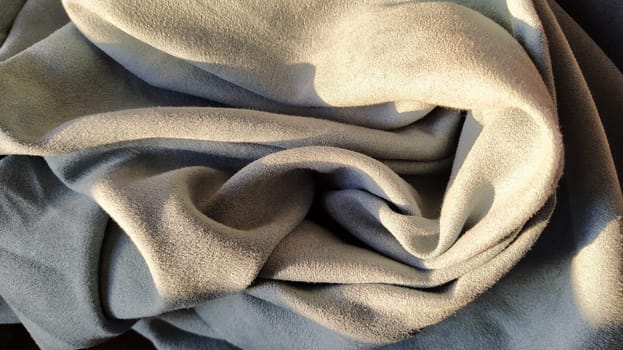 Gray-blue velvet curtains in the living room. The fabric is folded into waves. Short pile. The play of light and shadow in the folds of the garment. Beautiful,pleasant to the touch, expensive material