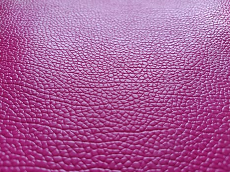 Artificial leather is bright pink or fuchsia. Distinct furrows and elevations on the surface of a bag or shoe. Reflection of the light. Fashion accessory made of imitation pig skin. Close-up.