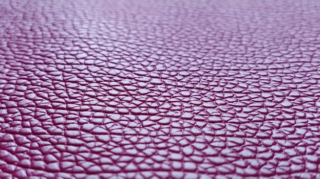 Artificial leather is bright pink or fuchsia. Distinct furrows and elevations on the surface of a bag or shoe. Reflection of the light. Fashion accessory made of imitation pig skin. Close-up.
