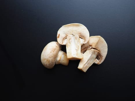 Champignons on a black background. Sliced and whole fresh uncooked raw mushrooms. Cooking mushrooms with a recipe