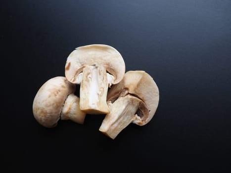 Champignons on a black background. Sliced and whole fresh uncooked raw mushrooms. Cooking mushrooms with a recipe