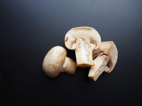 Champignons on a black background. Sliced and whole fresh uncooked raw mushrooms. Cooking mushrooms with a recipe