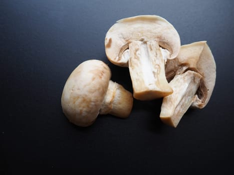 Champignons on a black background. Sliced and whole fresh uncooked raw mushrooms. Cooking mushrooms with a recipe