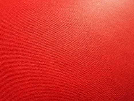 Abstract red background with texture. Close-up of paper surface with light and color gradient. Side lighting. Bright crimson backdrop.