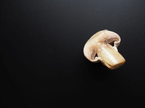 Champignons on a black background. Sliced and whole fresh uncooked raw mushrooms. Cooking mushrooms with a recipe