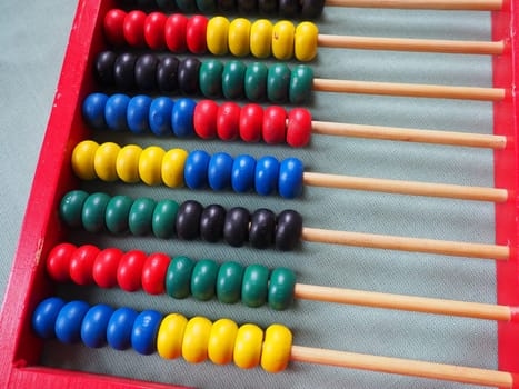 Education concept - abacus with many colorful beads. Red, blue, green, black, yellow details on the abacus. Mathematical exercises. School program.
