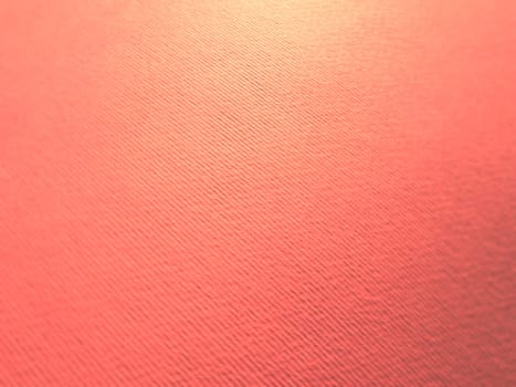 Abstract pink background with texture. Close-up of paper surface with light and color gradient. Side lighting. Soft pastel peach or ruddy tone backdrop