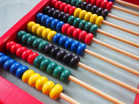 Education concept - abacus with many colorful beads. Red, blue, green, black, yellow details on the abacus. Mathematical exercises. School program.