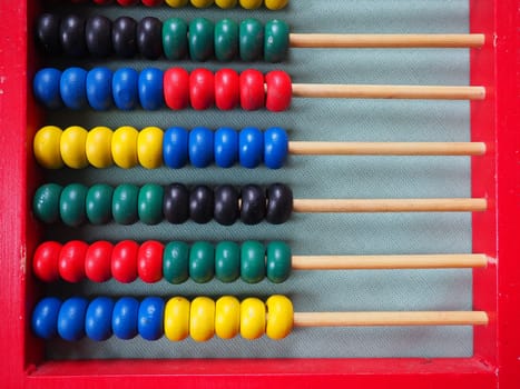Education concept - abacus with many colorful beads. Red, blue, green, black, yellow details on the abacus. Mathematical exercises. School program.