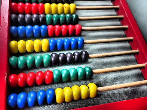 Education concept - abacus with many colorful beads. Red, blue, green, black, yellow details on the abacus. Mathematical exercises. School program.