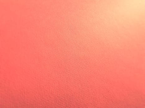 Abstract pink background with texture. Close-up of paper surface with light and color gradient. Side lighting. Soft pastel peach or ruddy tone backdrop