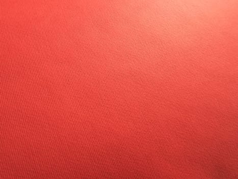 Abstract red background with texture. Close-up of paper surface with light and color gradient. Side lighting. Bright crimson backdrop.
