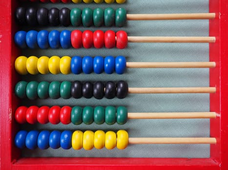Education concept - abacus with many colorful beads. Red, blue, green, black, yellow details on the abacus. Mathematical exercises. School program.