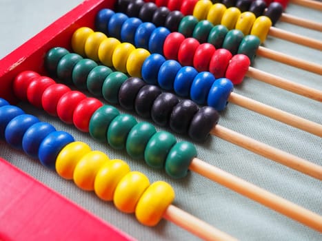 Education concept - abacus with many colorful beads. Red, blue, green, black, yellow details on the abacus. Mathematical exercises. School program.
