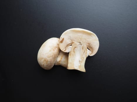 Champignons on a black background. Sliced and whole fresh uncooked raw mushrooms. Cooking mushrooms with a recipe