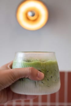 Hand holding iced matcha green tea, stock photo