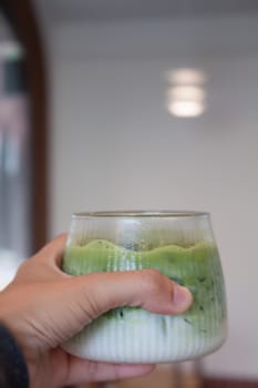 Hand holding iced matcha green tea, stock photo