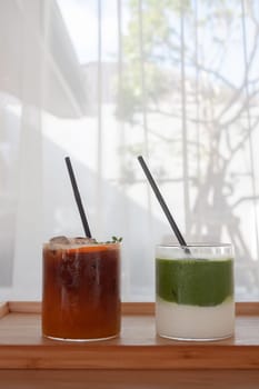 Iced americano with orange and iced matcha green tea in coffee shop, stock photo