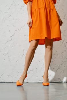 Beautiful female legs in orange stilettos and overknee dress
