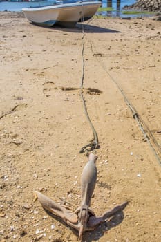 Anchor from fishing boat docked in low tide sand. Cabanas de Tavira, Portugal