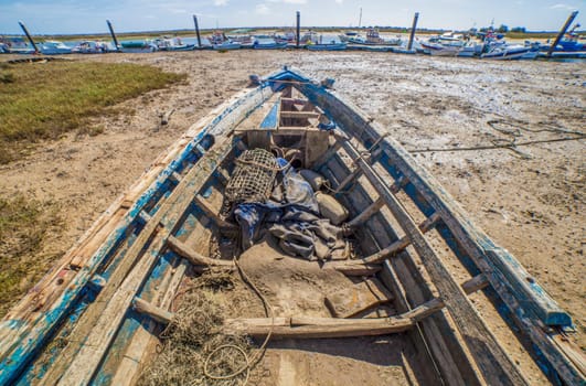Old wooden fishing boat docked in low tide sand. Cabanas de Tavira, Portugal