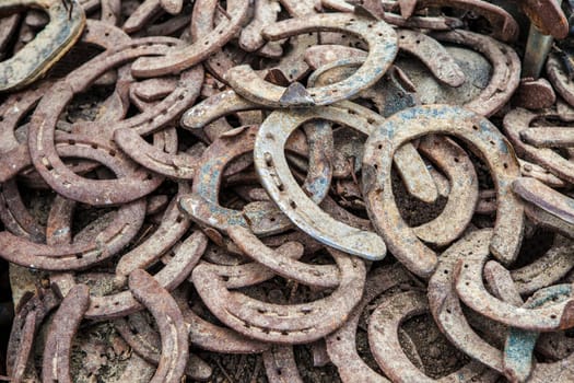 Pile of old used and rusty horseshoes. Selective focus