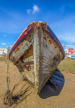 Old wooden fishing boat docked in low tide sand. Cabanas de Tavira, Portugal