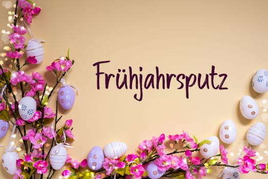 German Text Fruehjahrsputz Means Spring Cleaning On Beige Background. Pink And Purple, Shiny And Bright Spring Flower Arrangement With Easter Egg Decoration.