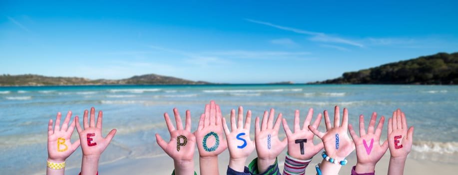 Children Hands Building Colorful English Word Be Positive. Summer Ocean, Sea And Beach As Background