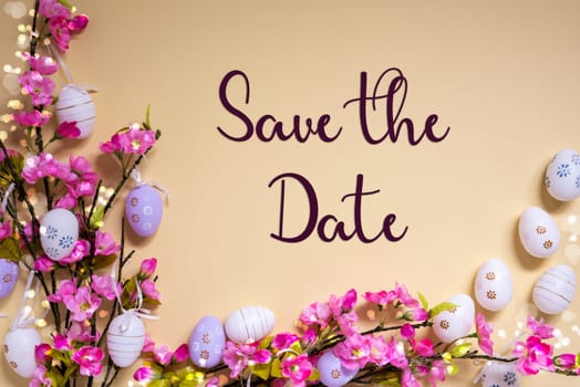 English Text Save The Date On Beige Background. Pink And Purple, Shiny And Bright Spring Flower Arrangement With Easter Egg Decoration.