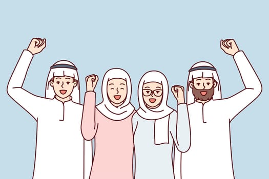 Team of people in arabic clothes make victory gestures rejoice at startup success. Modern men and women in Islamic clothing and headdresses raise their fist up with smile