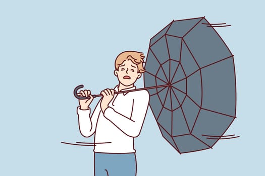 Man with umbrella turned backwards walks down street during severe life-threatening storm. Pedestrian in casual clothes caught in hurricane walking around city and needs shelter